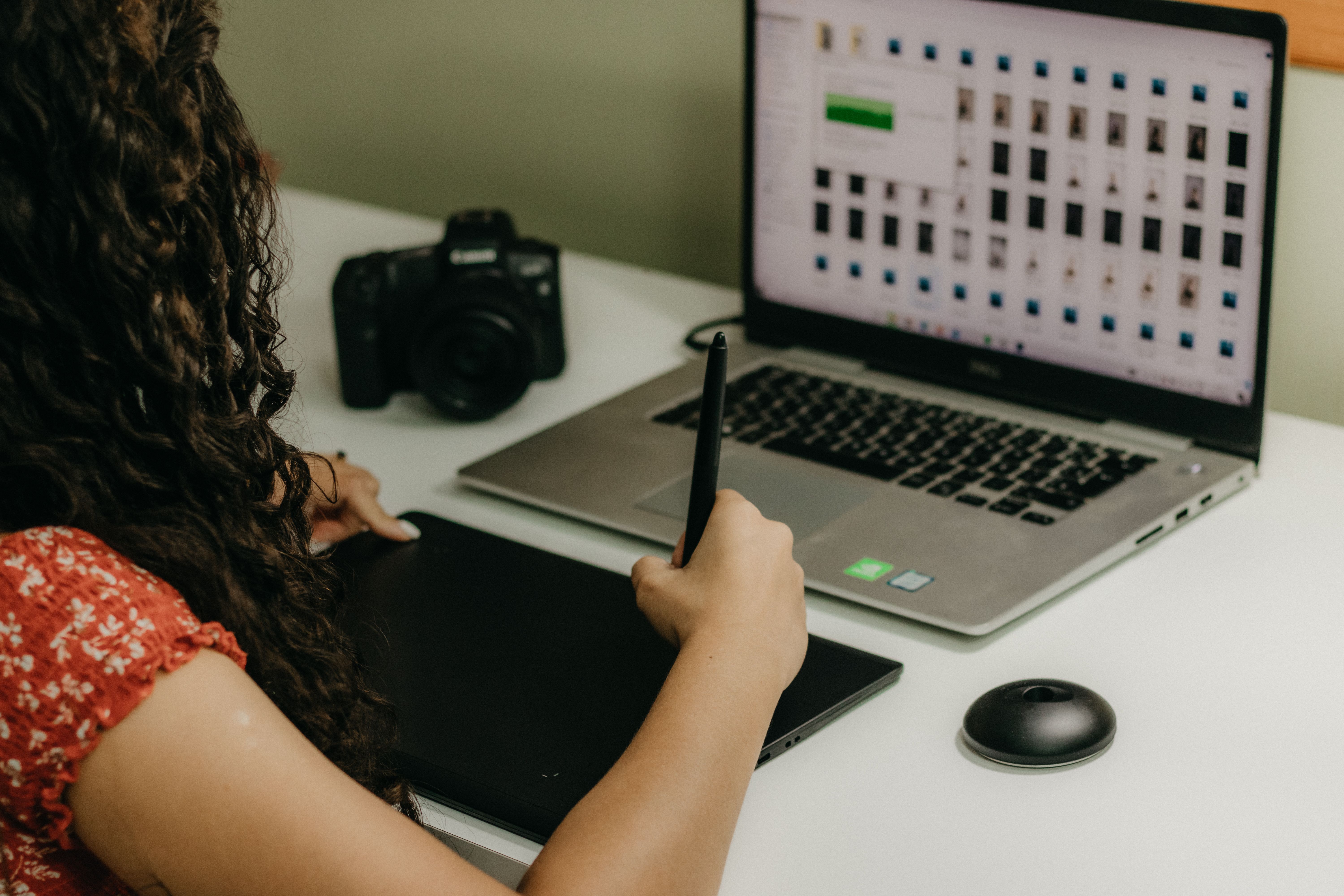 Designer working with a pen tablet and laptop in a digital content creation workspace