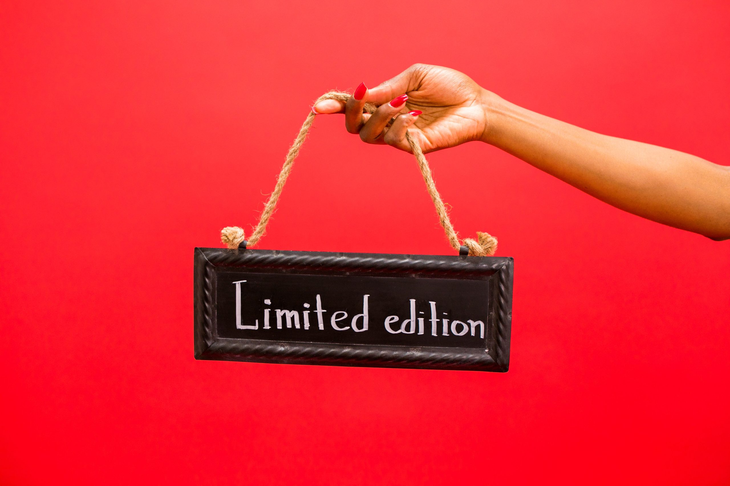 A hand holds a limited-edition sign against a vivid red background, illustrating the appeal of scarcity.