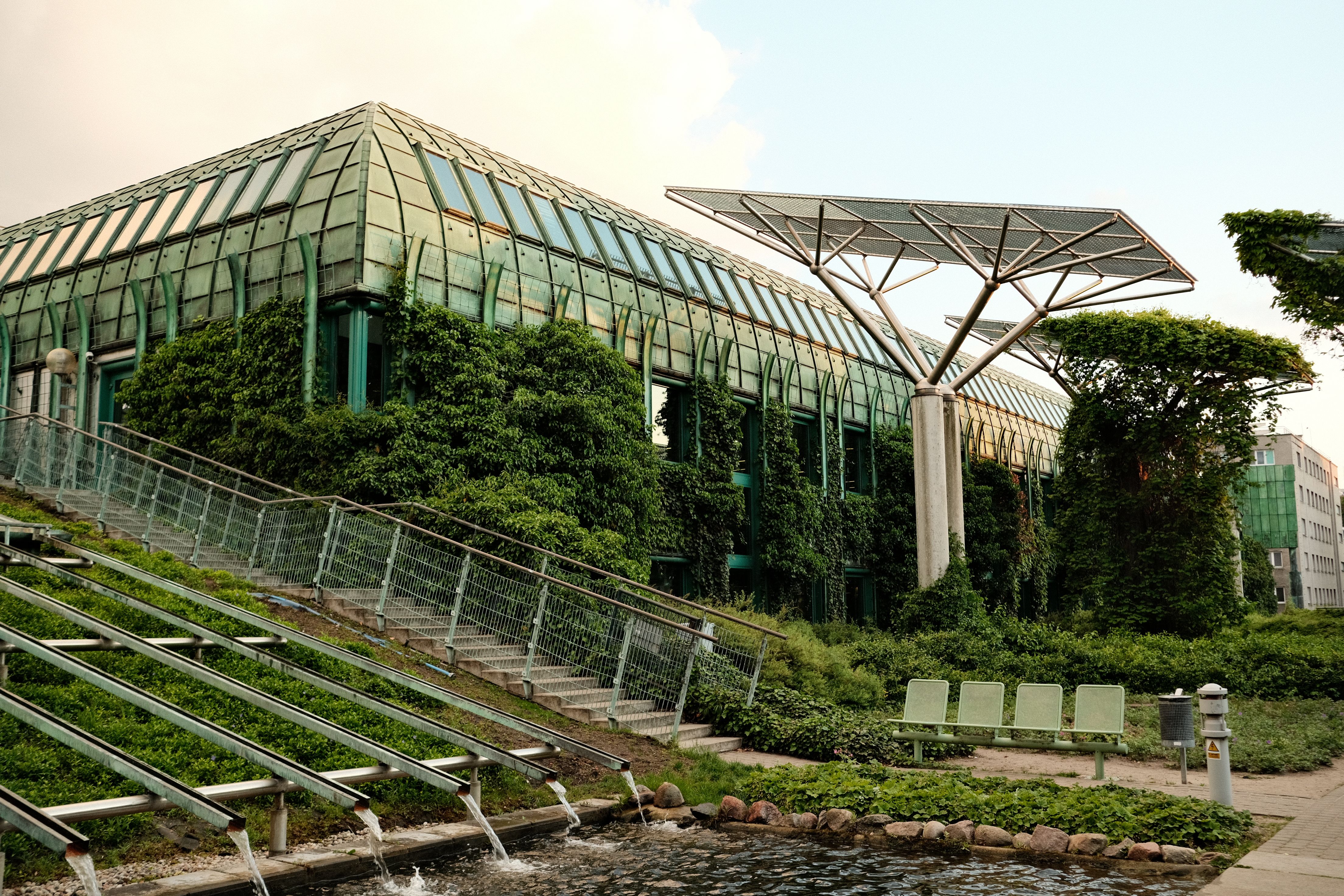 Eco-friendly urban building with rooftop gardens and solar panels, showing sustainability goals shaping construction.
